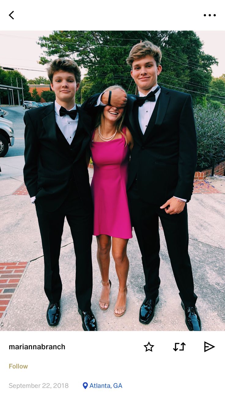 three young men in tuxedos posing for a photo together on the sidewalk with their arms around each other