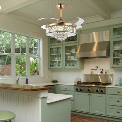 a kitchen with green cabinets and a chandelier hanging from the ceiling over the island