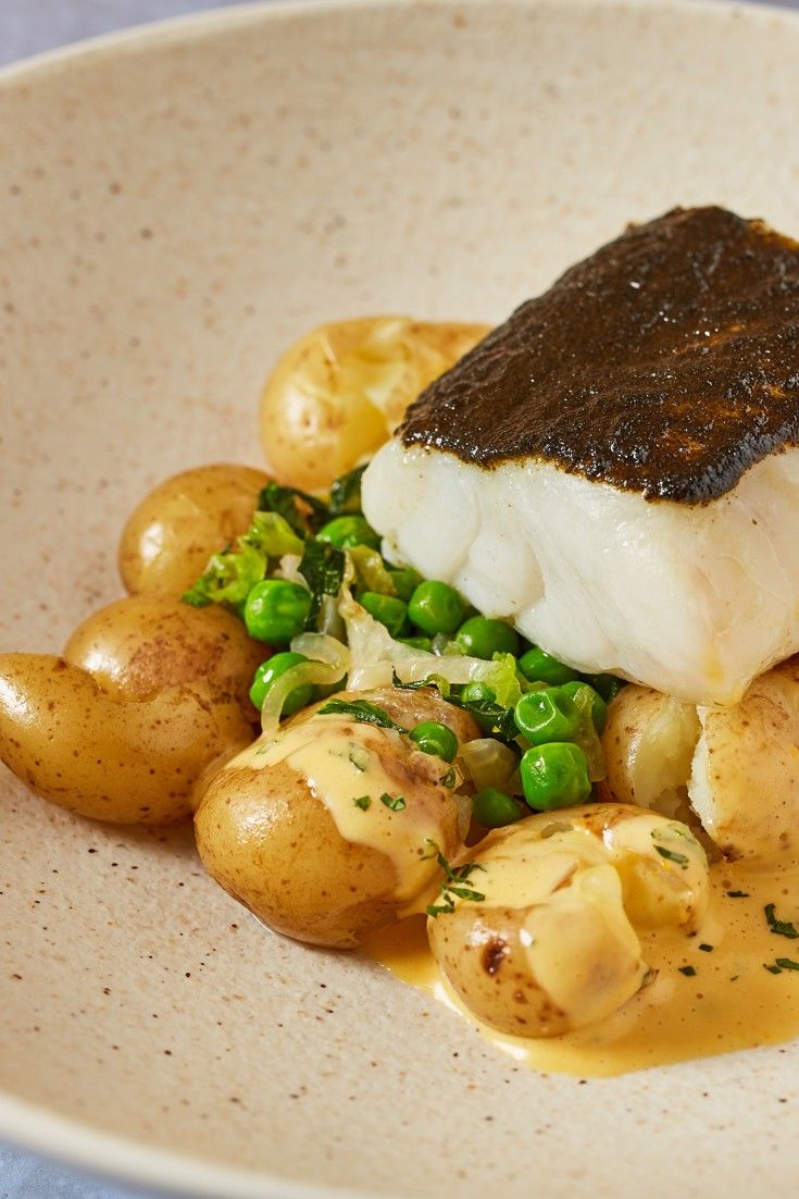 a white plate topped with fish and potatoes