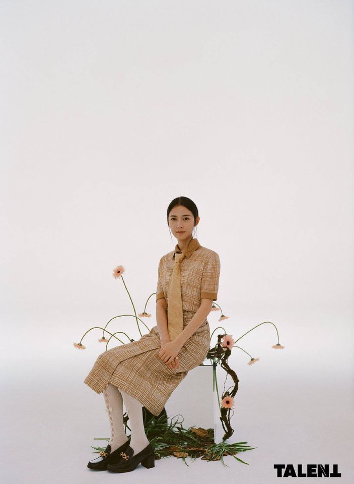 a woman sitting on top of a chair next to flowers