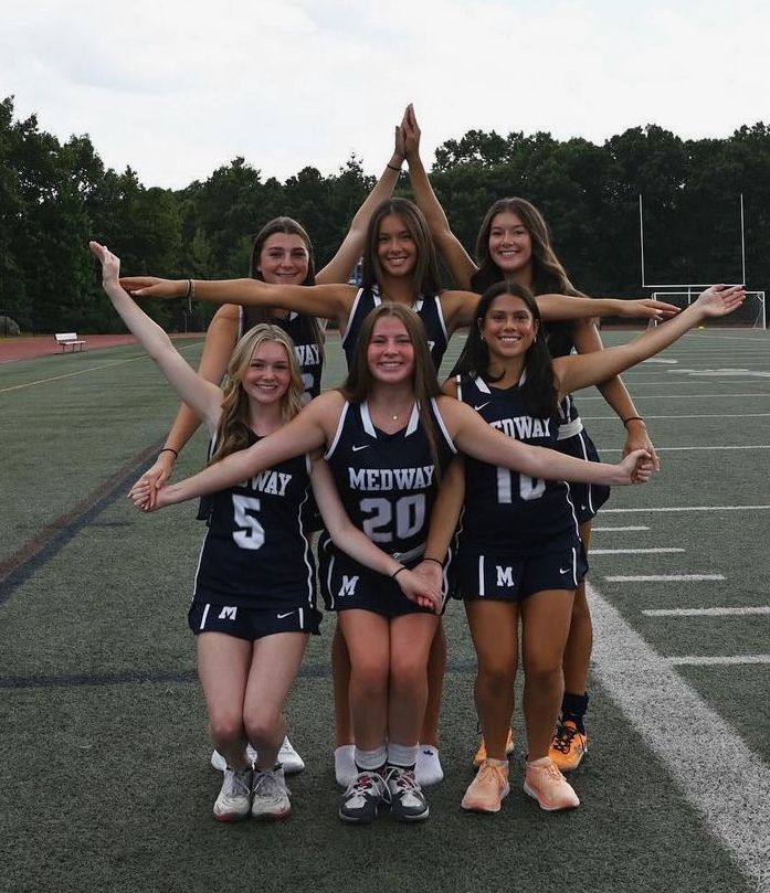 a group of young women standing next to each other on top of a field