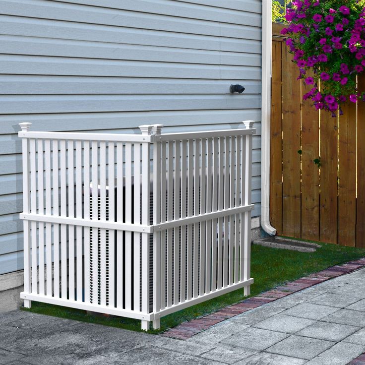 a white fence next to a house with purple flowers