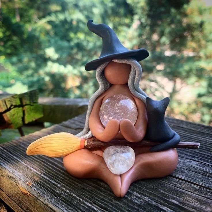 a figurine sitting on top of a wooden table next to a forest area