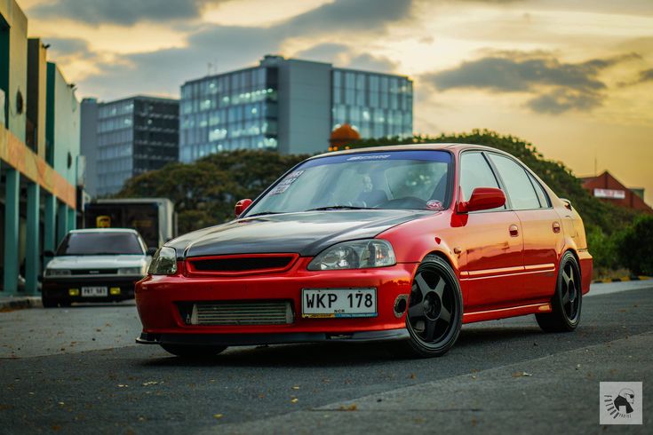 a red car is parked in front of some buildings