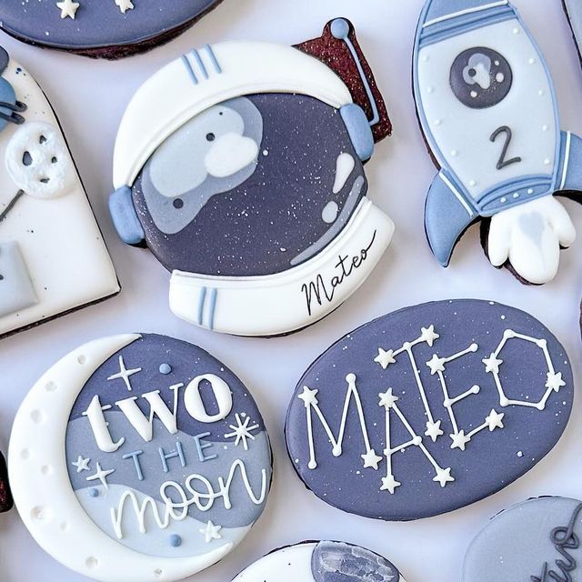 some cookies that are decorated to look like space shuttles and rockets with the words two the moon written on them