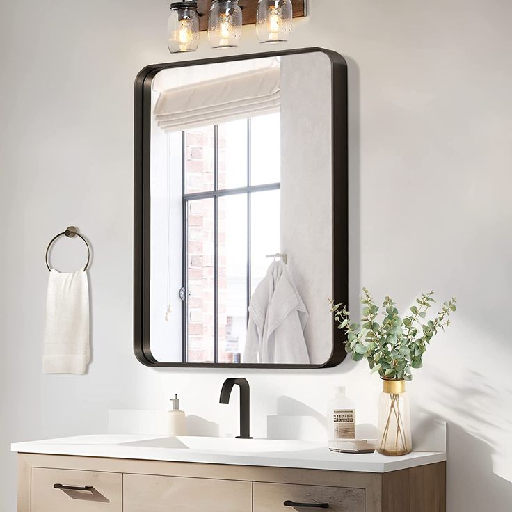 a bathroom with a sink, mirror and towels hanging on the rack in front of it