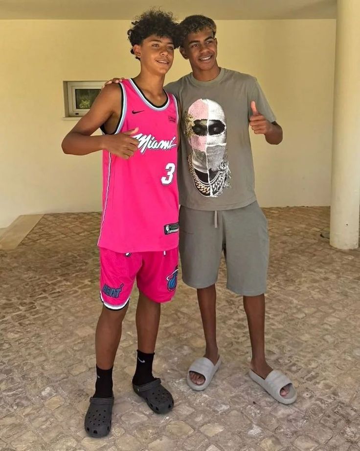 two young men standing next to each other in front of a wall with a skull on it