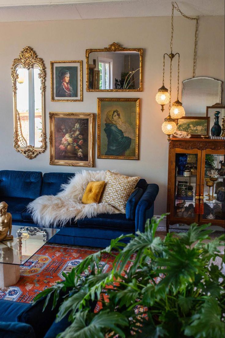 a living room filled with blue couches and pictures on the wall next to potted plants