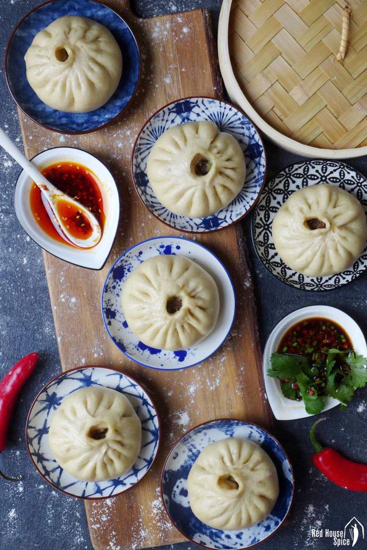 several small dumplings are sitting on plates with dipping sauces in bowls next to them