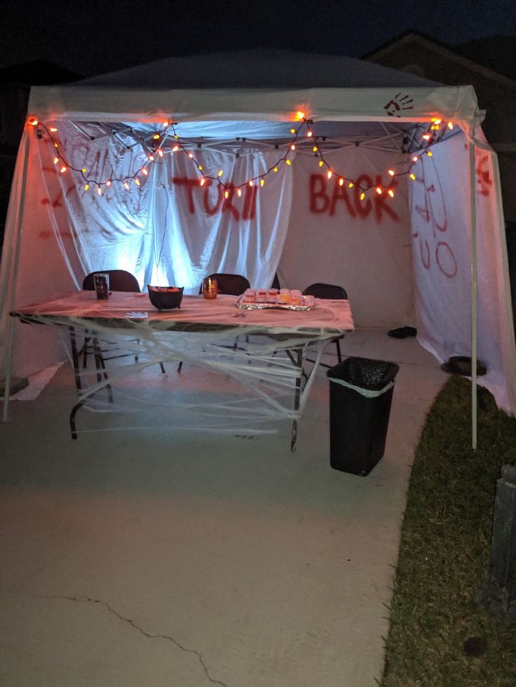 an outdoor tent with lights and curtains on the top is set up for a party