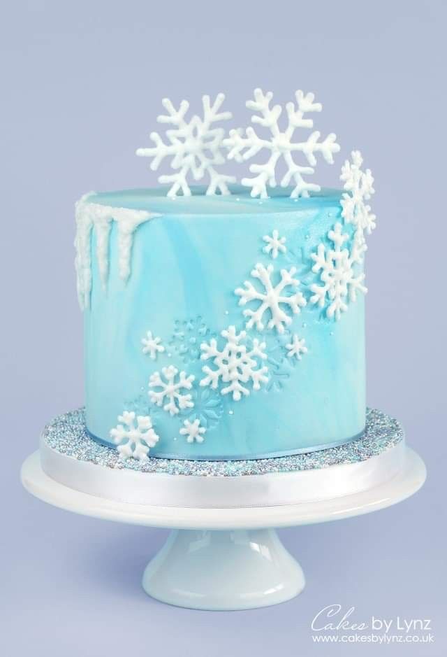 a blue frosted cake with white snowflakes on it