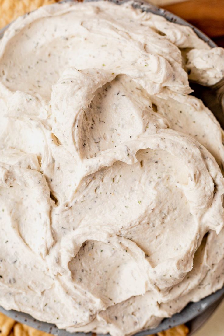 a bowl filled with whipped cream next to crackers