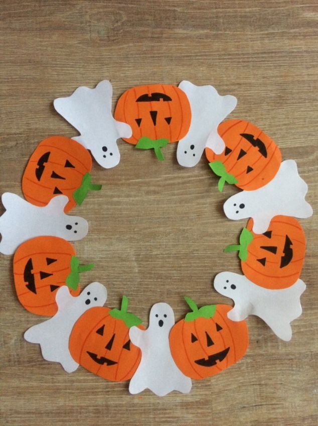 a paper wreath made to look like ghost and pumpkins