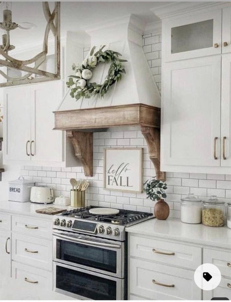 a kitchen with white cabinets, an oven and a wreath on the wall above it