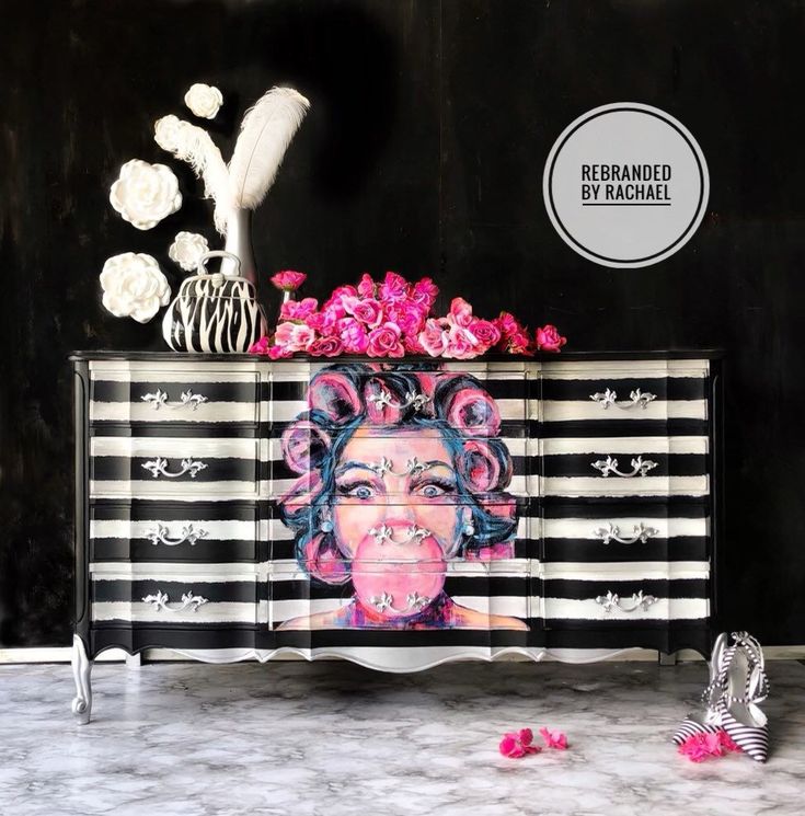 a black and white striped cabinet with pink flowers on the top is decorated with an image of a woman's face