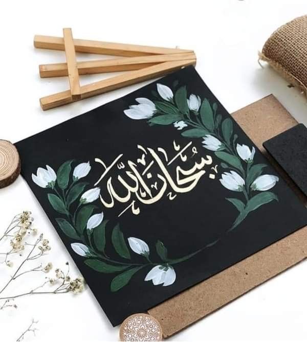 an arabic calligraphy on a black card surrounded by wood sticks and other crafting supplies