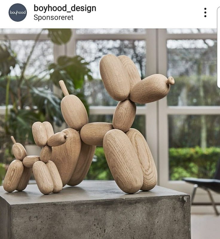 a wooden dog statue sitting on top of a cement block in front of a window