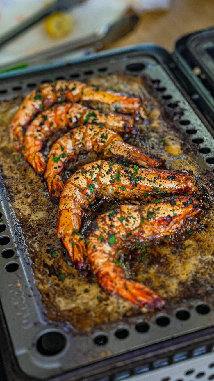 grilled shrimp being cooked in an oven with seasoning on the top and green sprinkles on the bottom