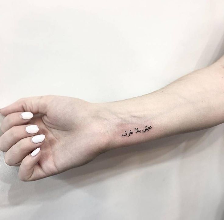 a woman's arm with an arabic writing tattoo on the left side of her hand