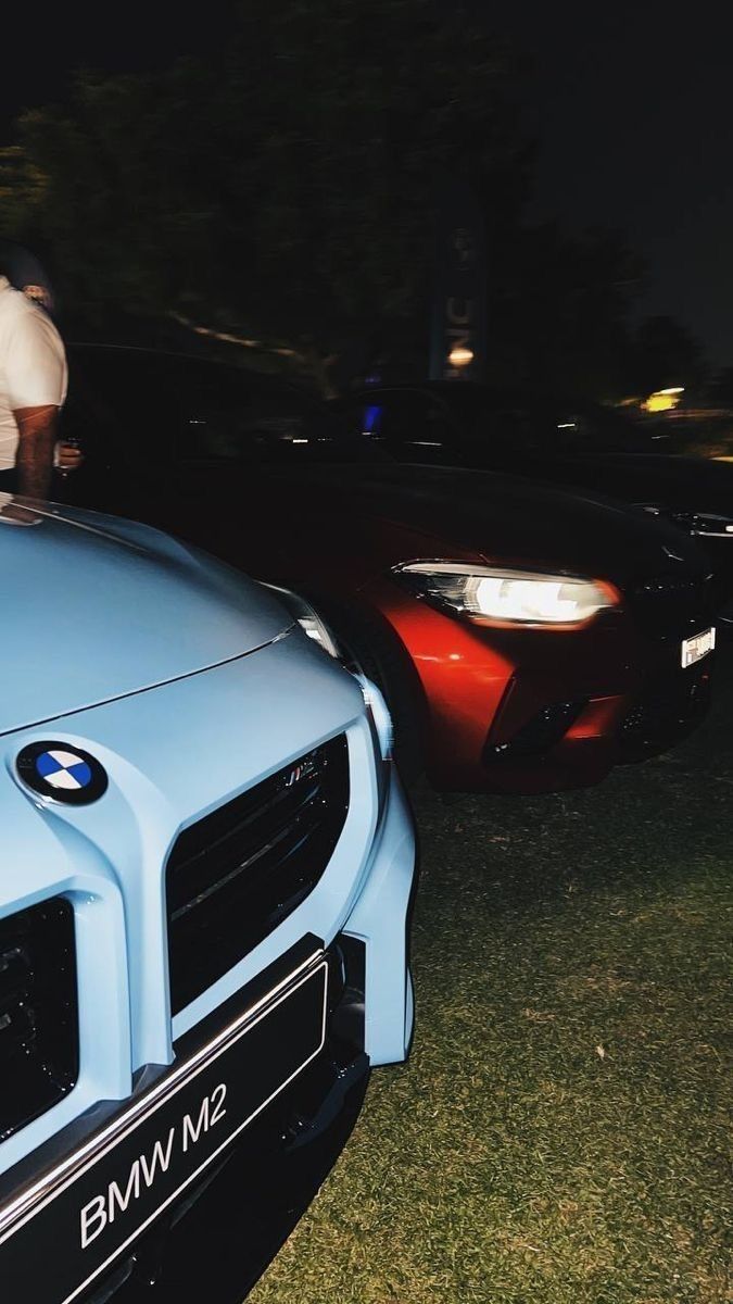 two cars parked next to each other in the grass at night with people standing on top