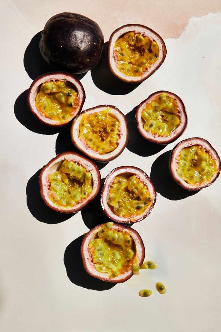 passion fruit cut in half on a white surface next to an avocado shell