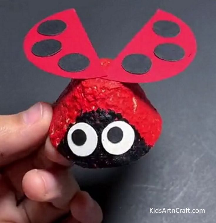 a hand holding up a rock with a ladybug painted on it