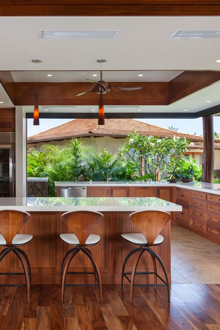 a large kitchen with wooden floors and white counter tops, along with two bar stools