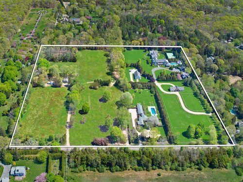 an aerial view of a large green field in the middle of a wooded area with lots of trees