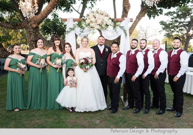 a group of people standing next to each other in front of a white and green wedding arch