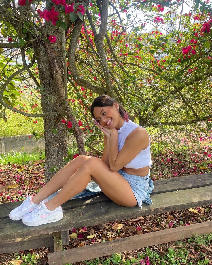 a woman sitting on a wooden bench next to a tree