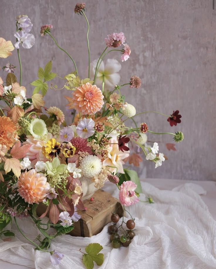 a bunch of flowers that are on top of a white cloth and some kind of wooden block