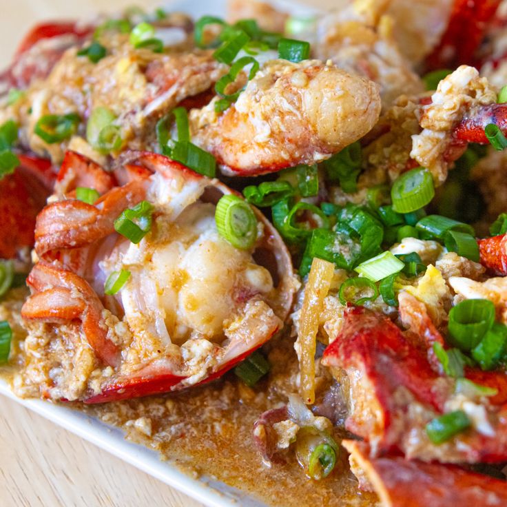 a plate full of cooked lobsters and other food on top of a wooden table