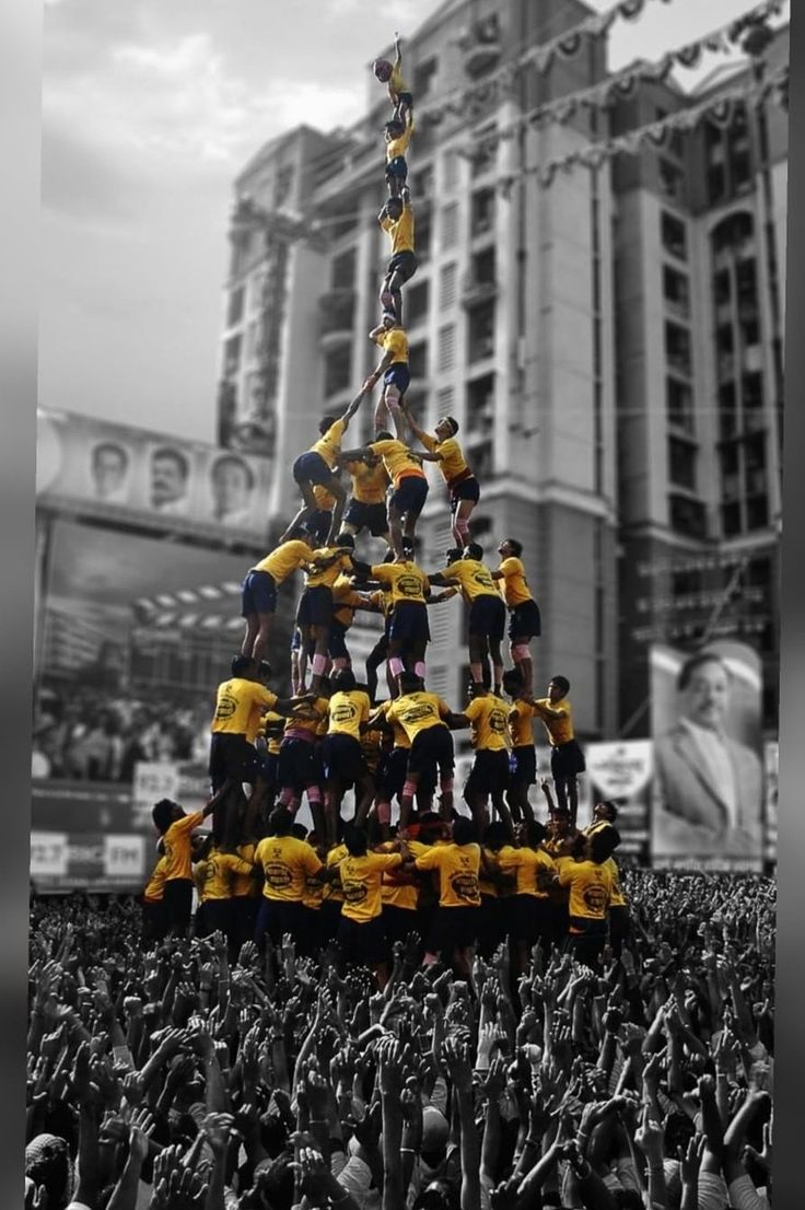 a group of people standing on top of a christmas tree in the middle of a crowd