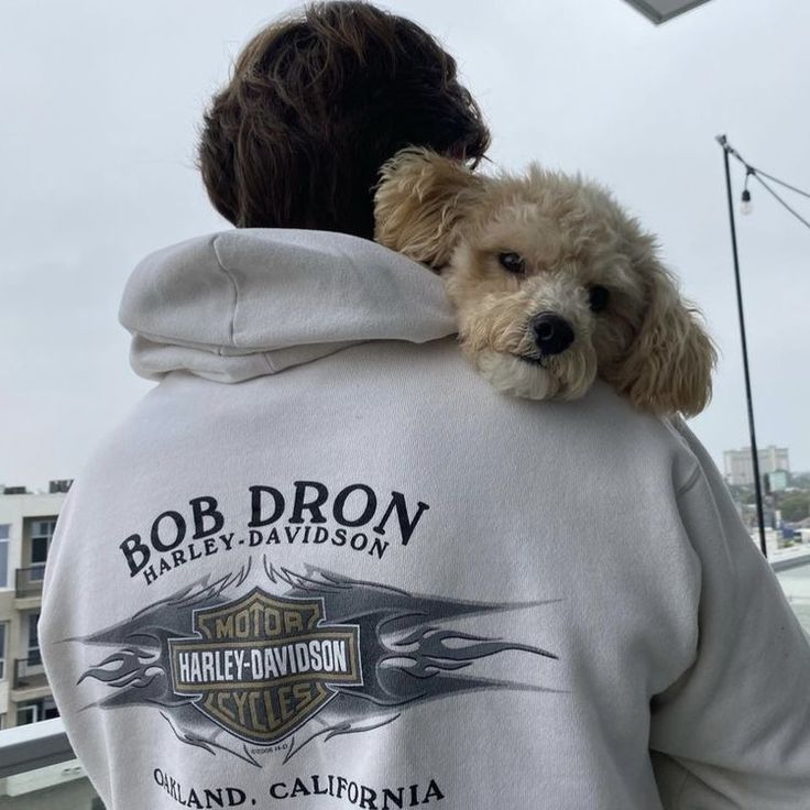 a dog is sitting on the back of a man's hoodie that says bob dron harley davidson