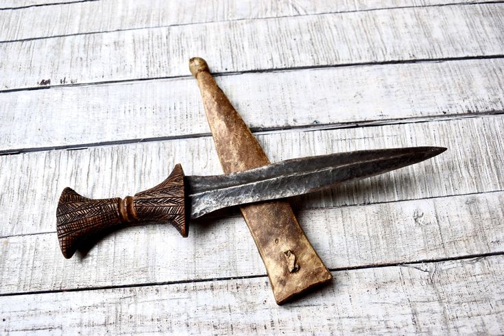 an old knife is laying on top of a piece of wood