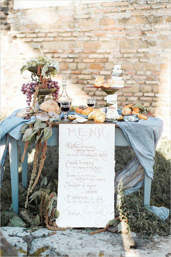 a table set up with food and drinks for a wedding reception in front of a brick wall