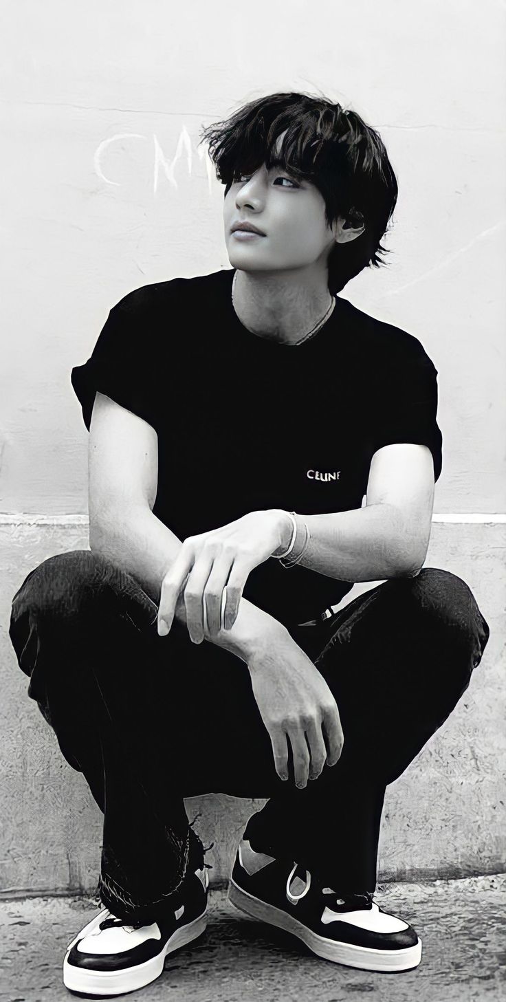 black and white photograph of a young man sitting on the ground with his hands crossed