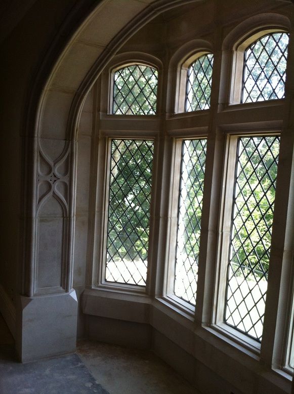 an arched window in the corner of a room with stone and glass work on it