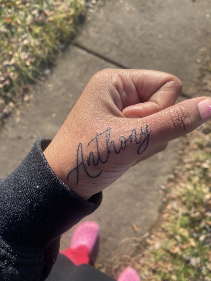 a person with a tattoo on their hand that says, nattoryy in cursive writing