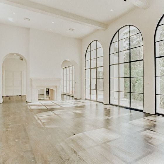 an empty living room with large windows and wood floors