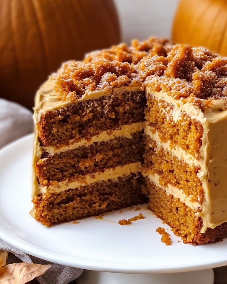 there is a cake that has been cut in half on a white plate with two pumpkins behind it