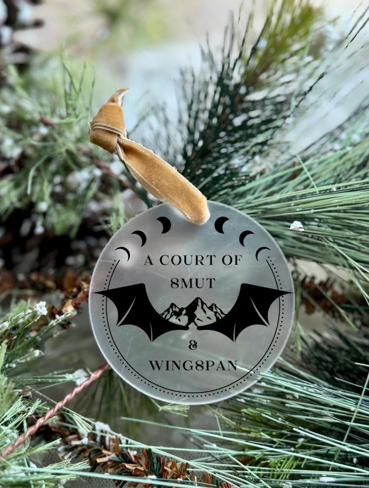 a glass ornament with a bat hanging from a pine tree in the snow