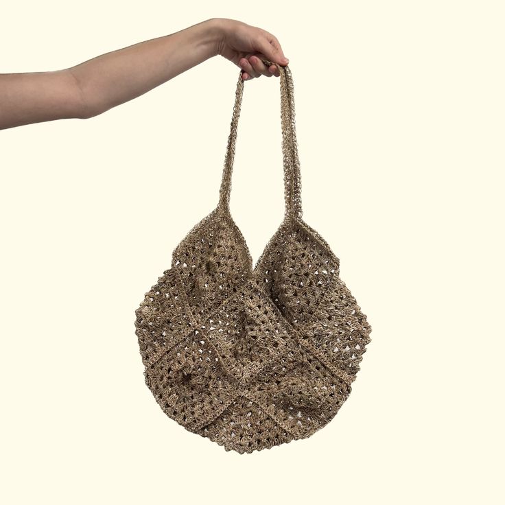 a woman's hand is holding a purse made out of crocheted material