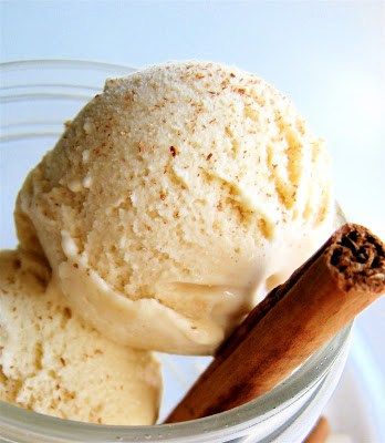 two scoops of vanilla ice cream in a glass jar with cinnamon stick on top