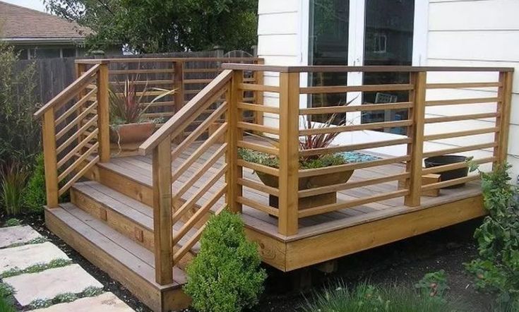 a wooden deck with planters on it and steps leading to the front door area