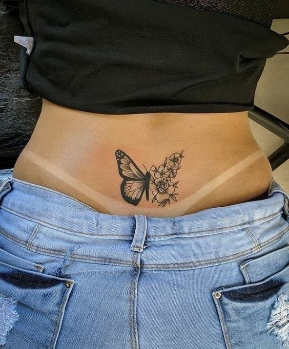 a woman's stomach with a butterfly and flowers tattoo on her side ribcage