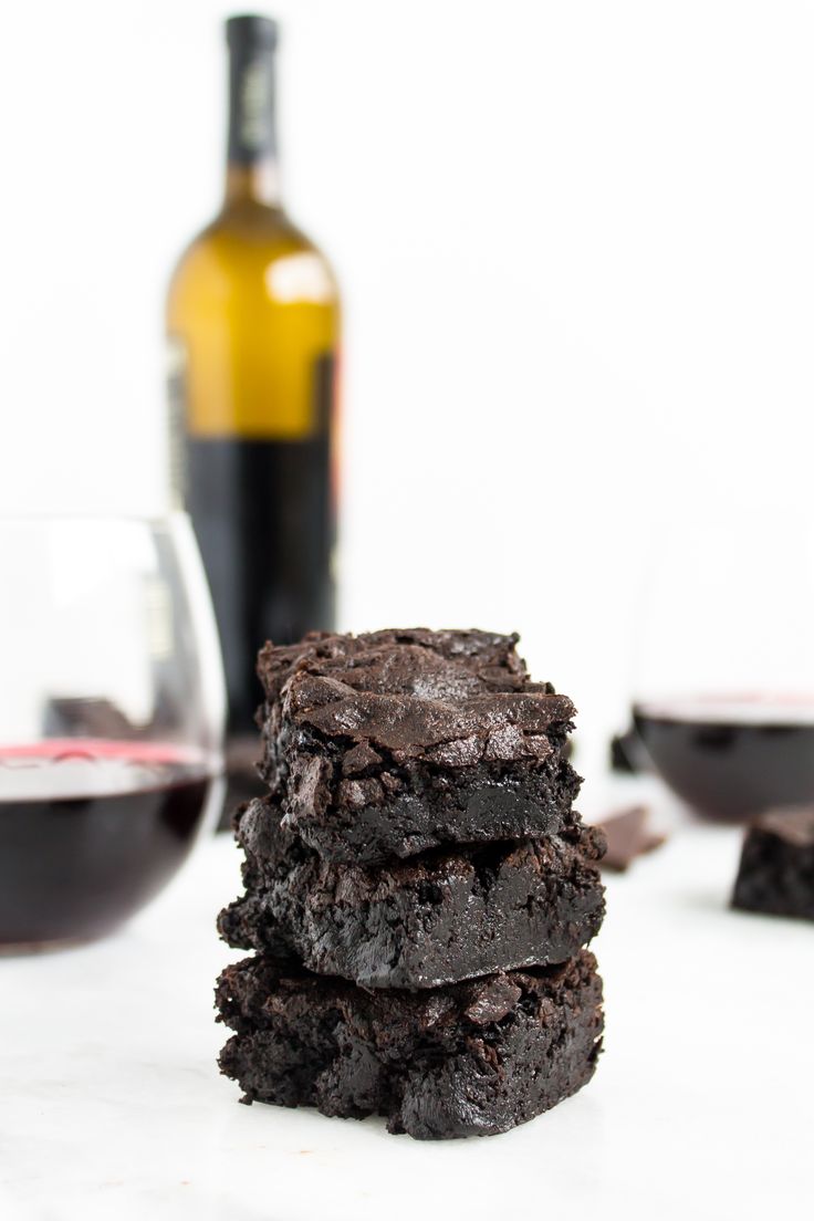 three brownies stacked on top of each other next to a bottle of wine