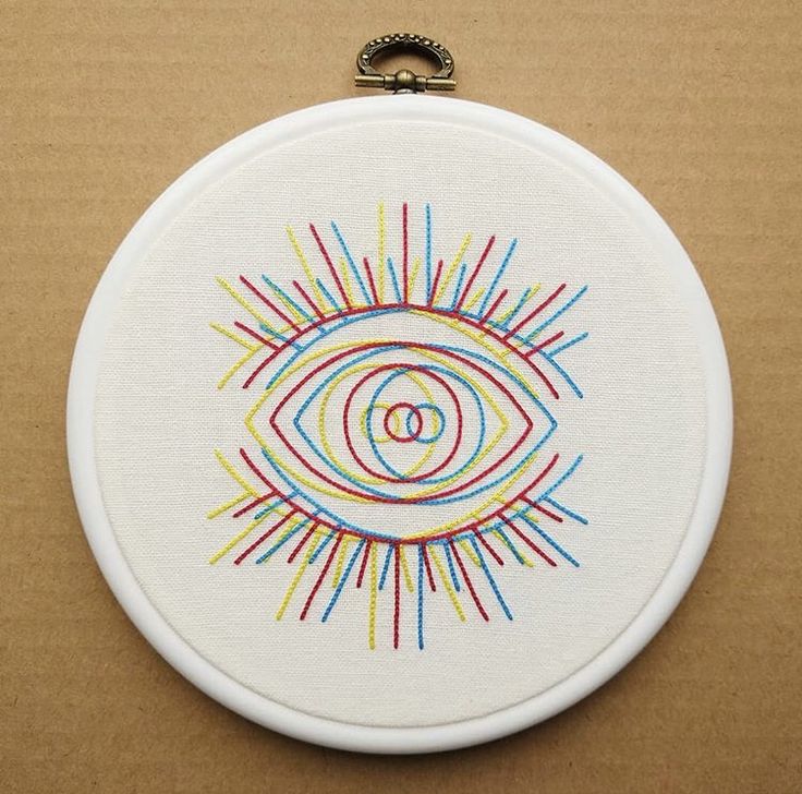 an embroidery project is displayed on a table with a white circle and colorful lines in the center