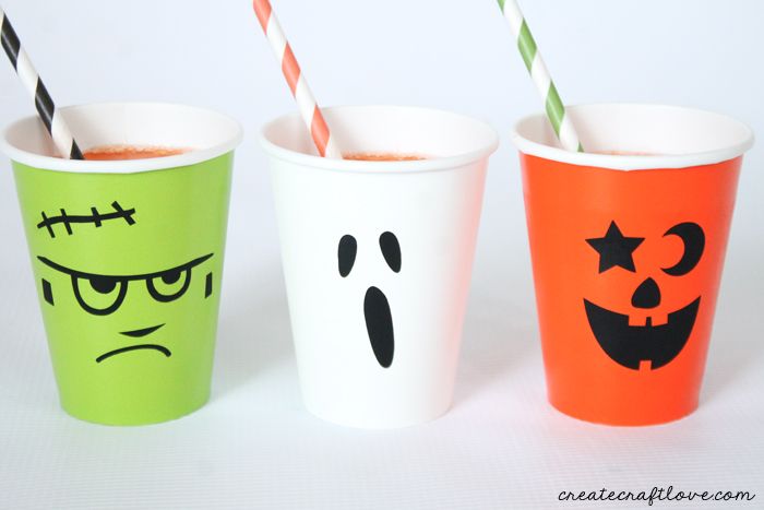 three halloween cups with straws in them and faces painted on the sides, one is orange, one is green