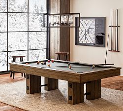 a pool table in the middle of a room with large windows and wood flooring